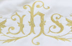 Close-up of gold embroidered IHS monogram with scrolling vines on cream canopy fabric